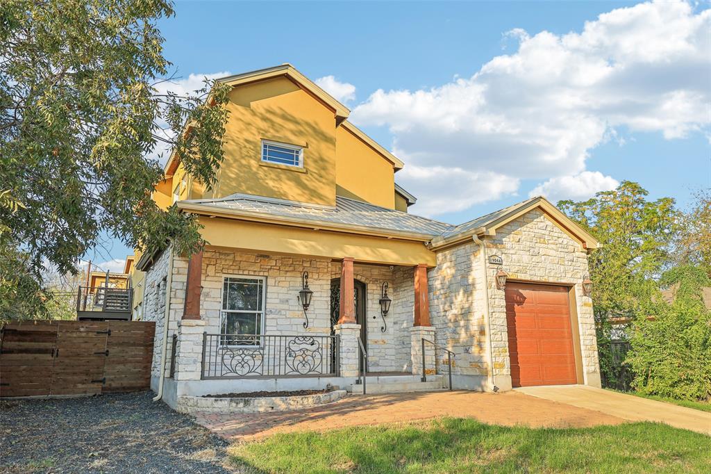 1904 East 13th Street, Unit A Austin, TX 78702 - Photo 1 of 27 View of front of house featuring stone siding, an attached garage, a porch, and driveway
