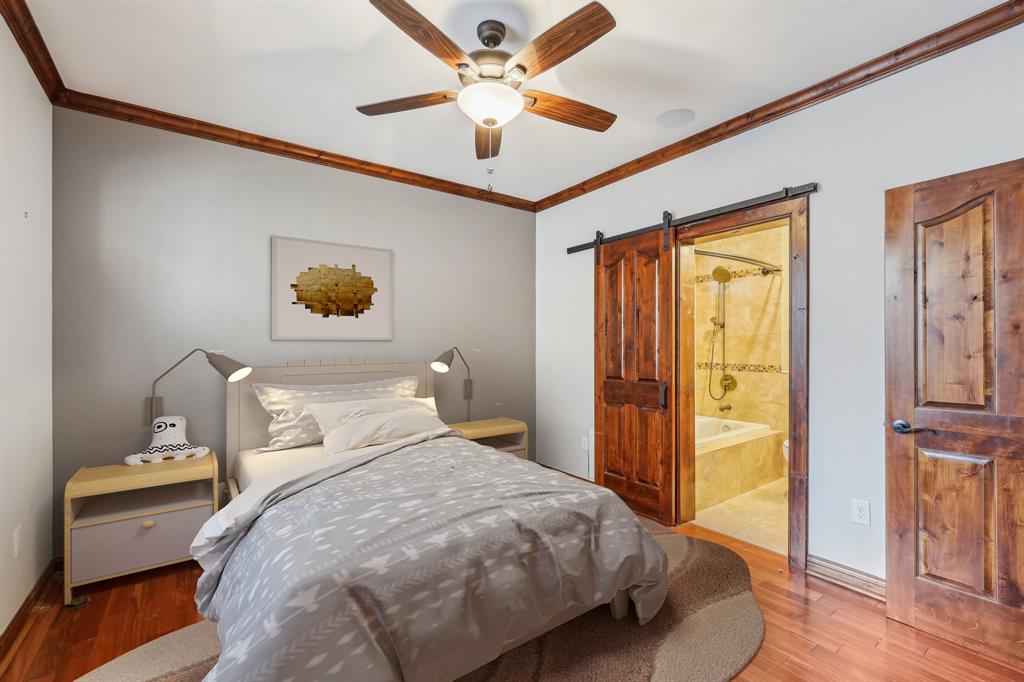 1904 East 13th Street, Unit A Austin, TX 78702 - Photo 18 of 27 Bedroom featuring crown molding, a barn door, wood finished floors, a ceiling fan, and ensuite bathroom