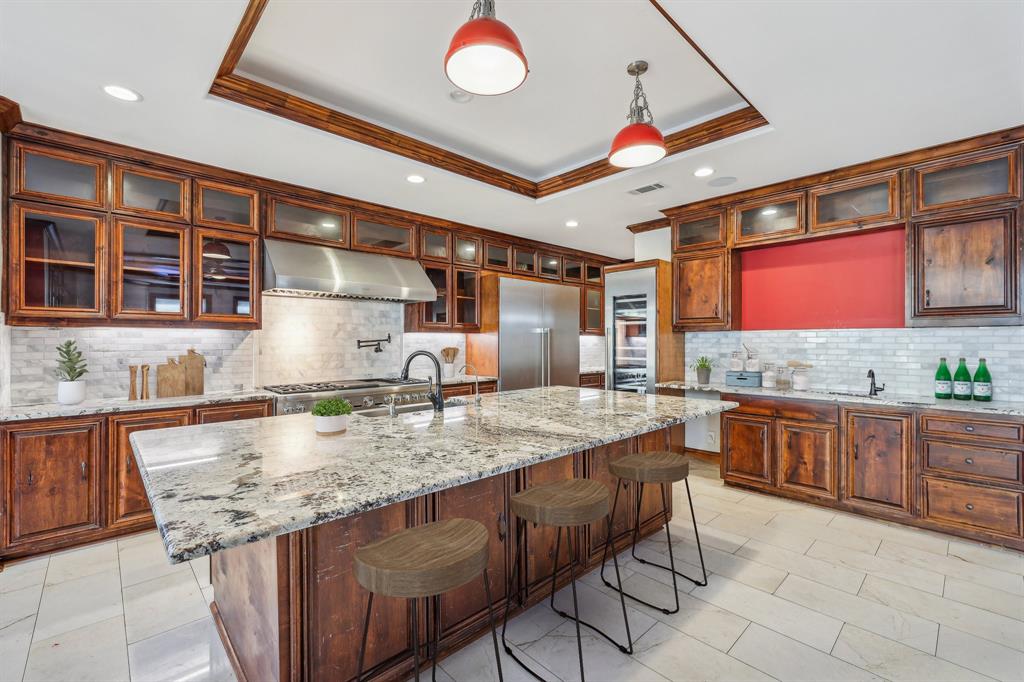 1904 East 13th Street, Unit A Austin, TX 78702 - Photo 8 of 27 Kitchen featuring a raised ceiling, decorative backsplash, light stone countertops, a kitchen breakfast bar, and under cabinet range hood