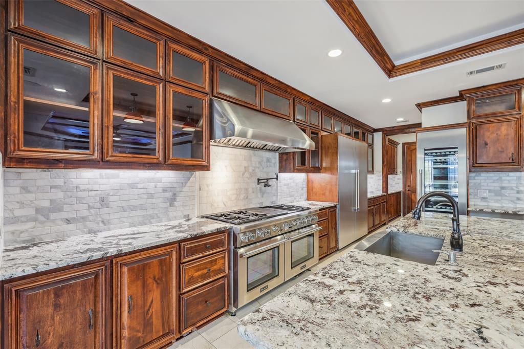 1904 East 13th Street, Unit A Austin, TX 78702 - Photo 9 of 27 Kitchen featuring tasteful backsplash, light stone counters, high quality appliances, crown molding, and under cabinet range hood