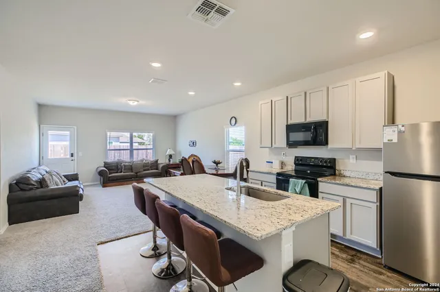 a kitchen with sink refrigerator dining table and chairs