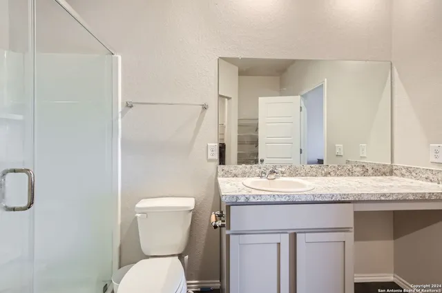 a bathroom with a granite countertop toilet sink and mirror