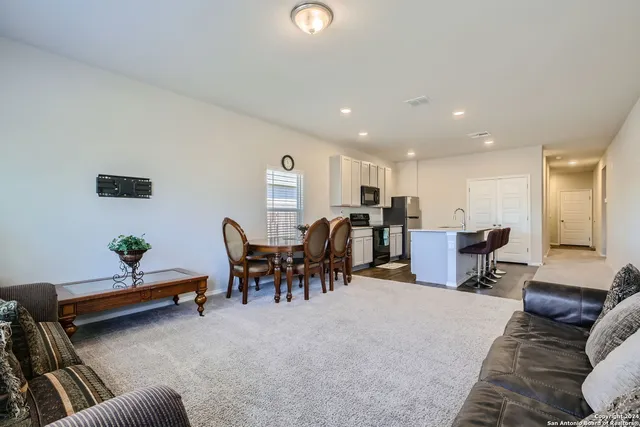 a living room with furniture and a dining table with kitchen view