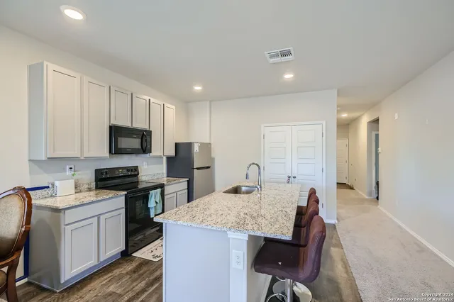 a kitchen with stainless steel appliances granite countertop a stove a sink a microwave a refrigerator and cabinets