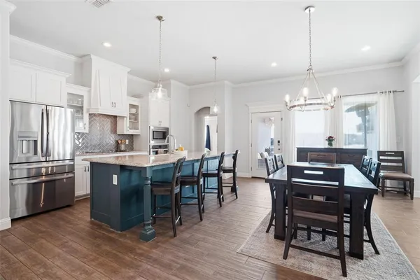 a kitchen with stainless steel appliances a dining table chairs stove and refrigerator