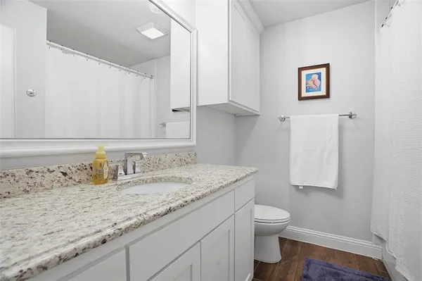 a bathroom with a granite countertop sink a toilet and a mirror