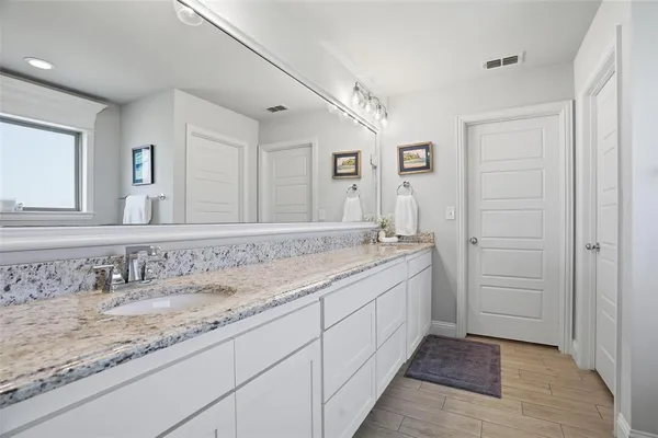 a bathroom with a granite countertop double vanity sink and a mirror