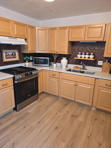 a kitchen with stainless steel appliances granite countertop a stove a sink and white cabinets