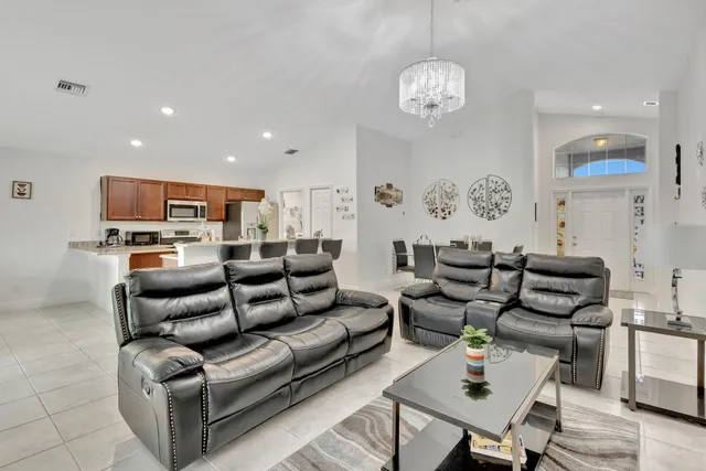 a living room with furniture kitchen view and a chandelier