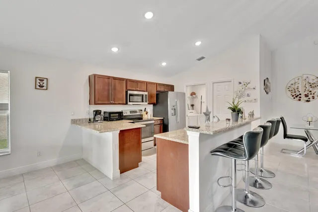 a living room with stainless steel appliances furniture a dining table and kitchen view