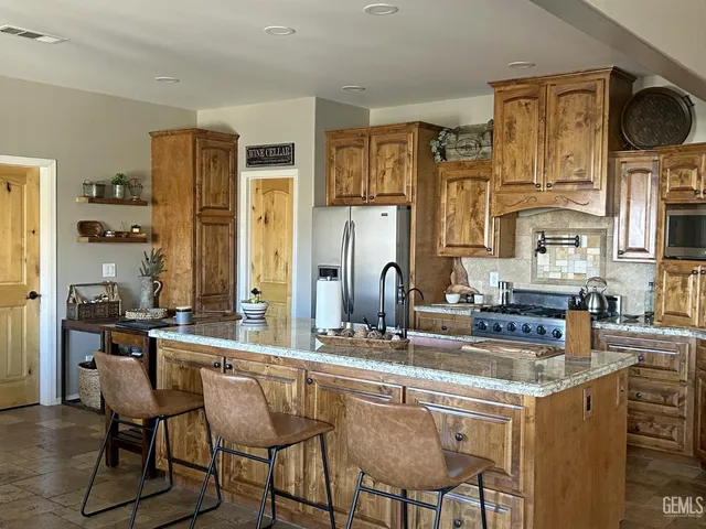a kitchen with stainless steel appliances kitchen island granite countertop a table chairs in it and wooden floors