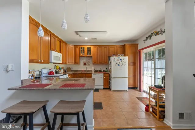 a kitchen with stainless steel appliances granite countertop a refrigerator a sink dishwasher and white cabinets with wooden floor