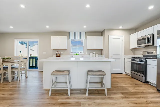 a large white kitchen with wooden floor and stainless steel appliances