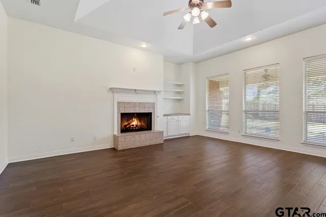 a view of an empty room with wooden floor fireplace and a window