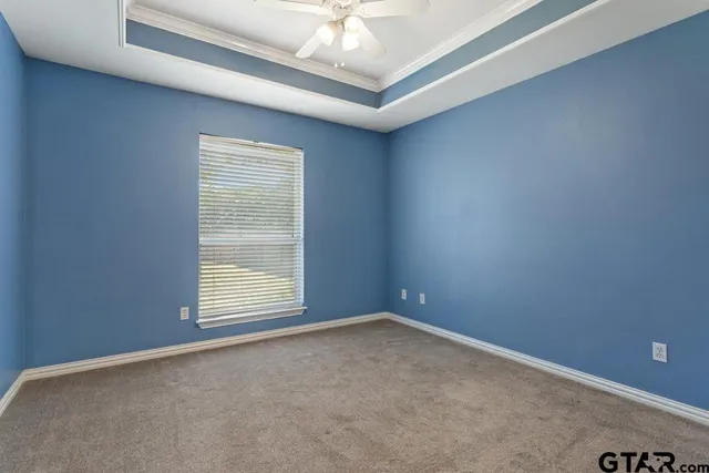 an empty room with a chandelier fan and windows