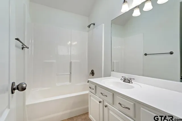 a bathroom with a tub sink double vanity and a mirror