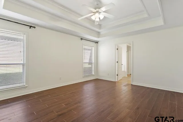 an empty room with wooden floor and a ceiling fan