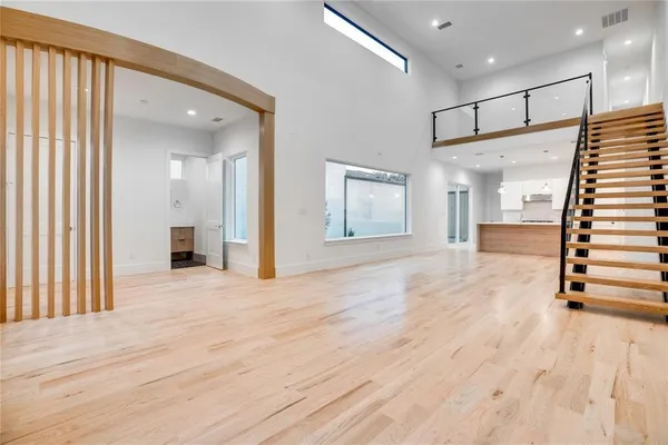 a view of an empty room with wooden floor and a balcony