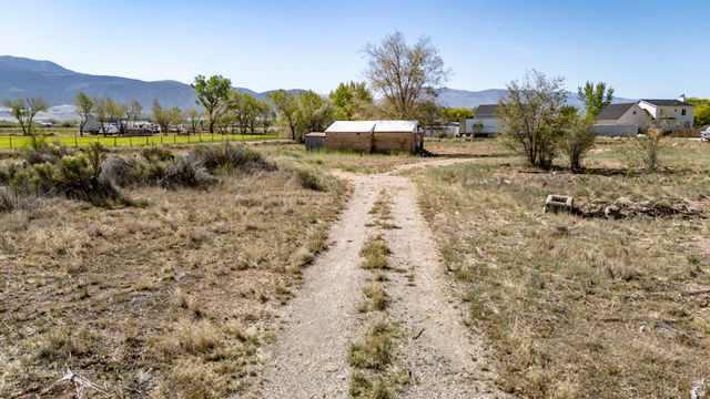 1211 West Midvalley Road Cedar City, UT 84721 - Photo 14 of 14 Expansive rural land featuring a gravel driveway and a brick outbuilding with a metal roof