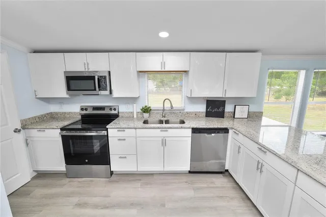 a kitchen with stainless steel appliances granite countertop a stove a sink and a microwave