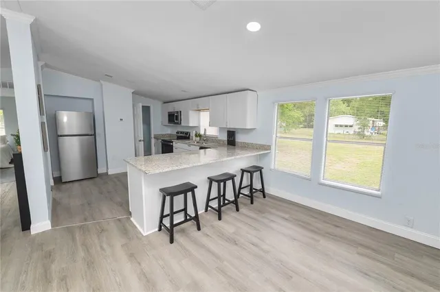 a kitchen with stainless steel appliances a dining table chairs refrigerator and sink