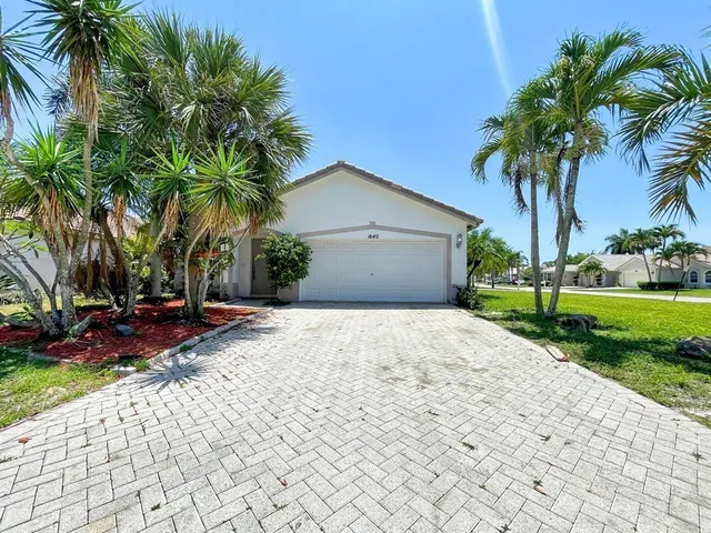a front view of a house with garden and a yard