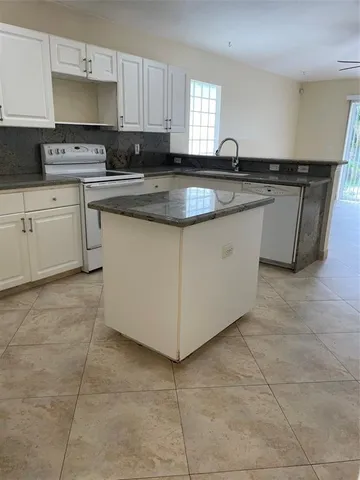 a kitchen with granite countertop a sink a stove a microwave a counter top and cabinets