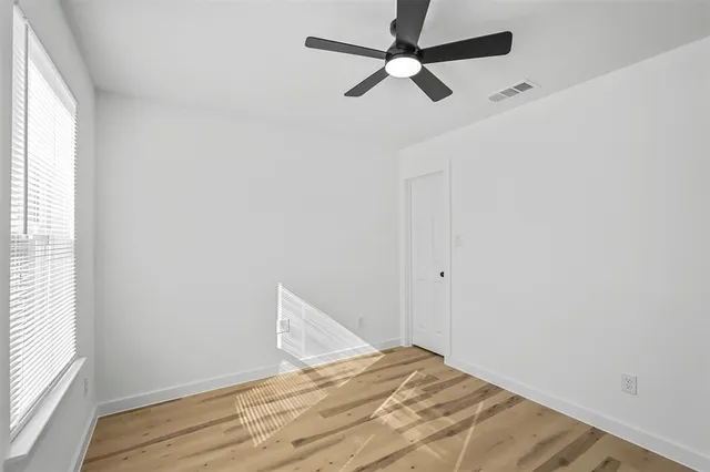 a view of empty room with wooden floor and fan