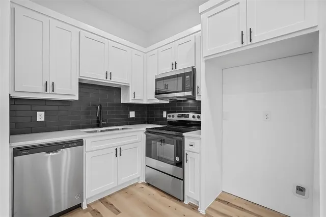 a kitchen with white cabinets stainless steel appliances and sink