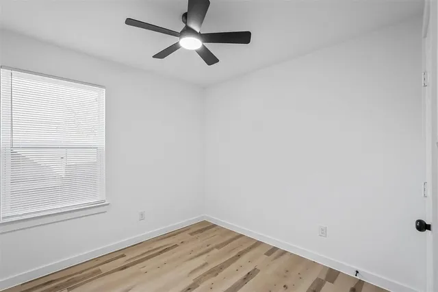an empty room with a window and a ceiling fan