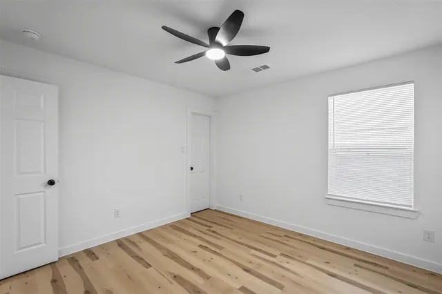 a view of empty room with wooden floor and ceiling fan