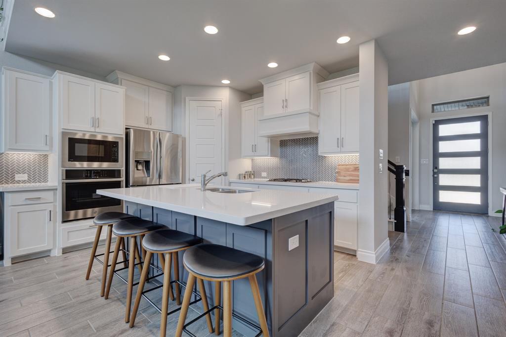830 Knoxbridge Road Forney, TX 75126 - Photo 14 of 36 a kitchen with stainless steel appliances a dining table chairs refrigerator and microwave