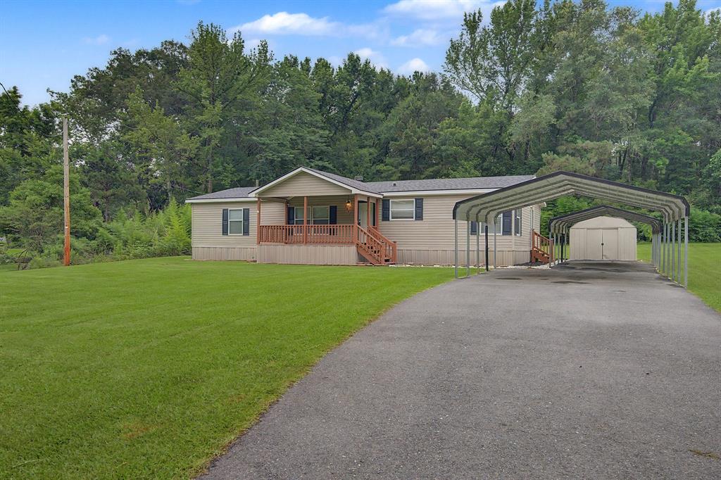 Single-story residence featuring a covered front porch with wood railings and steps, set on a spacious lawn