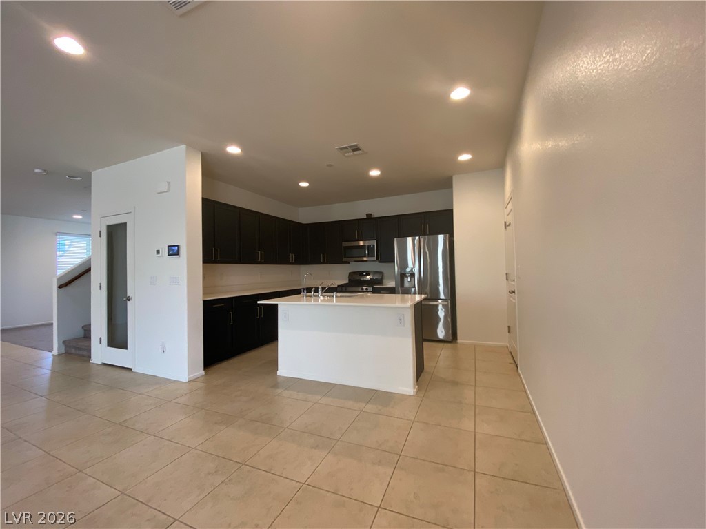 436 Cadence View Way Henderson, NV 89011 - Photo 2 of 36 A contemporary kitchen space boasts sleek dark cabinetry, stainless steel appliances, and a central island.