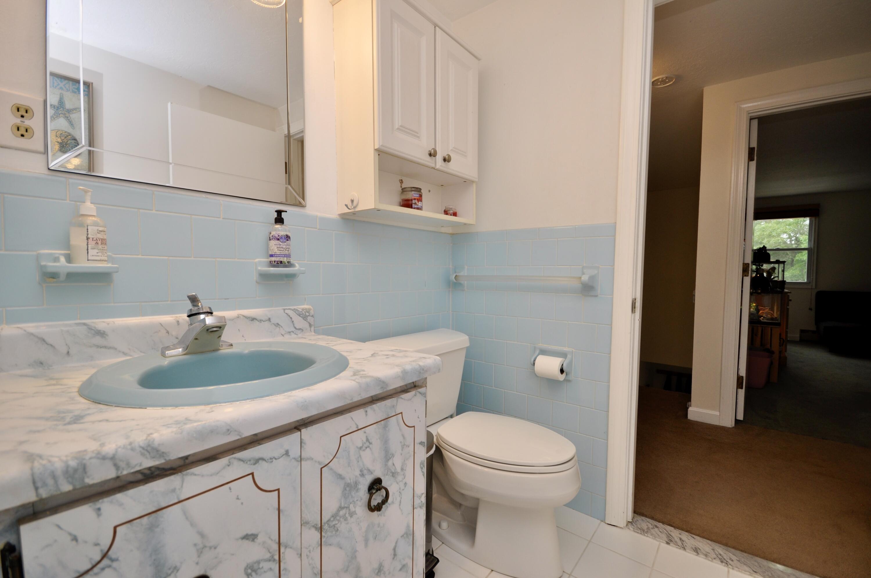 401 Village Drive Bourne, MA 02532 - Photo 13 of 22 a bathroom with a granite countertop toilet a sink and a mirror