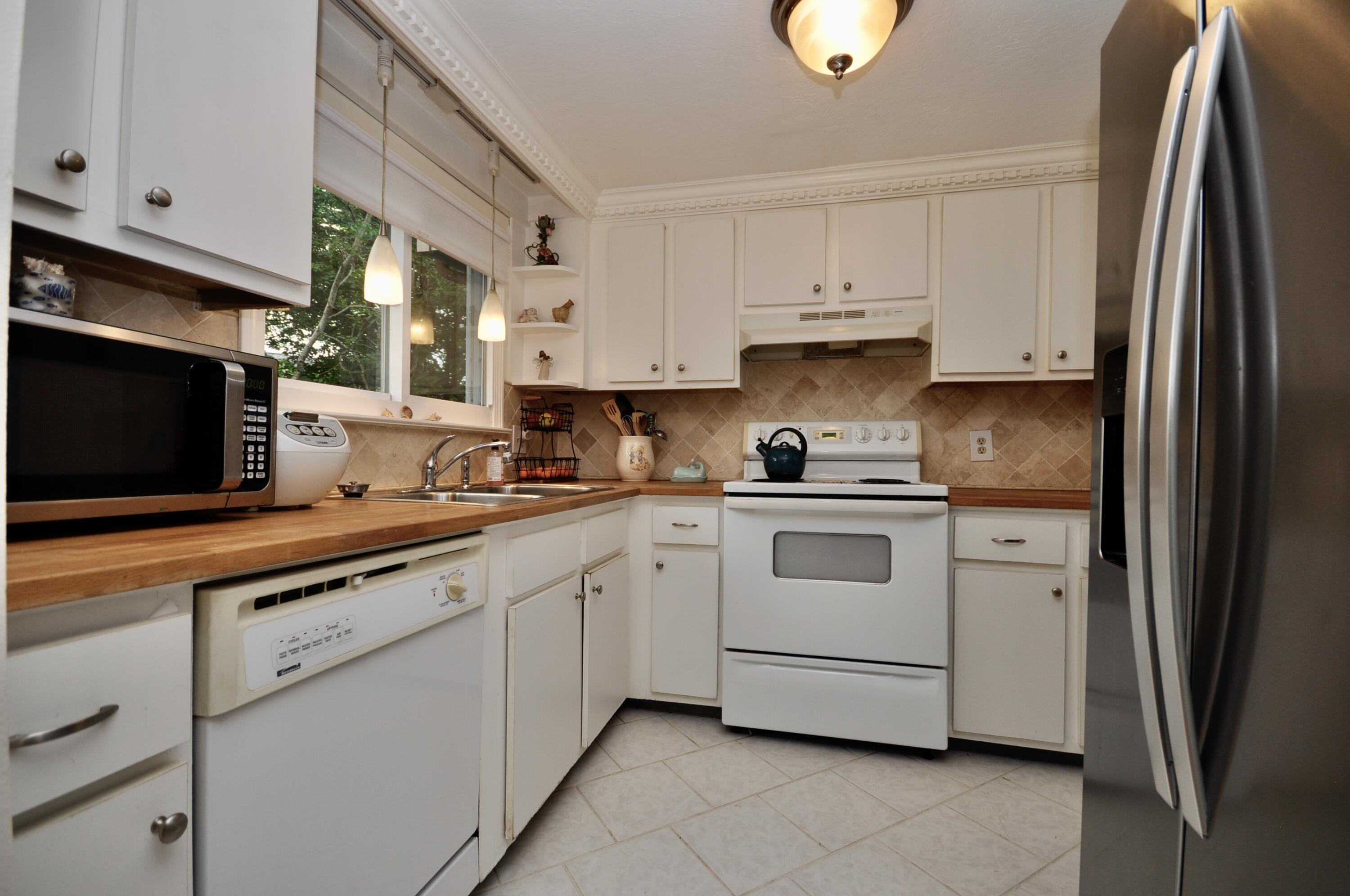 401 Village Drive Bourne, MA 02532 - Photo 7 of 22 a white kitchen with stainless steel appliances granite countertop a stove a sink and a refrigerator
