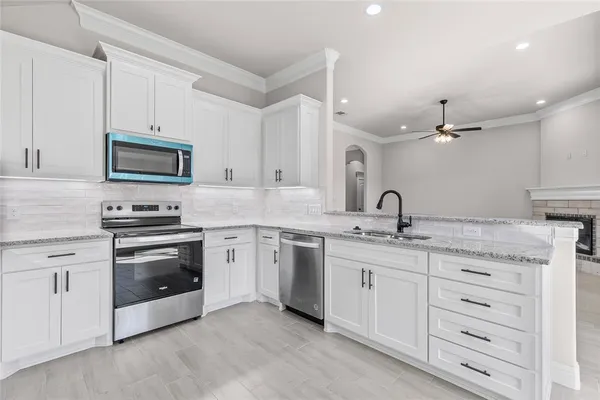 a kitchen with granite countertop white cabinets and stainless steel appliances