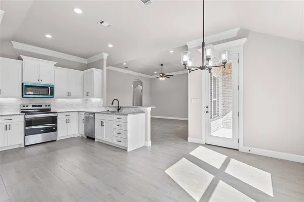 a large white kitchen with a refrigerator a stove a sink and a cabinets
