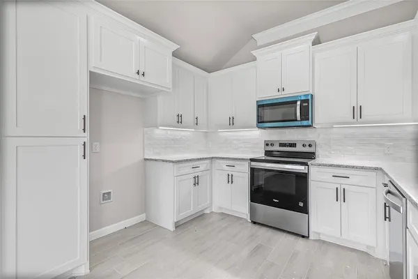 a kitchen with granite countertop white cabinets and stainless steel appliances
