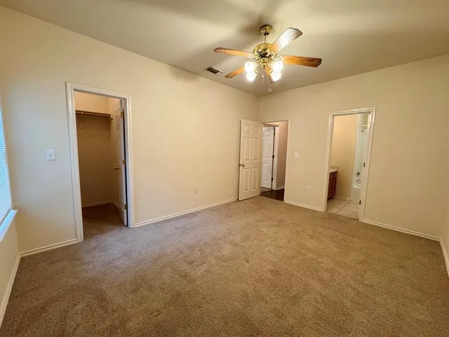 a view of an empty room with a chandelier fan
