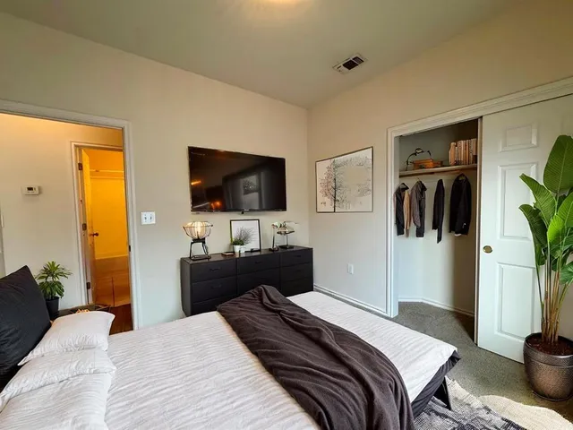 a bedroom with a bed and a flat tv screen on dresser
