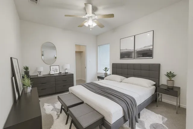 a bedroom with a bed table chair and a chandelier