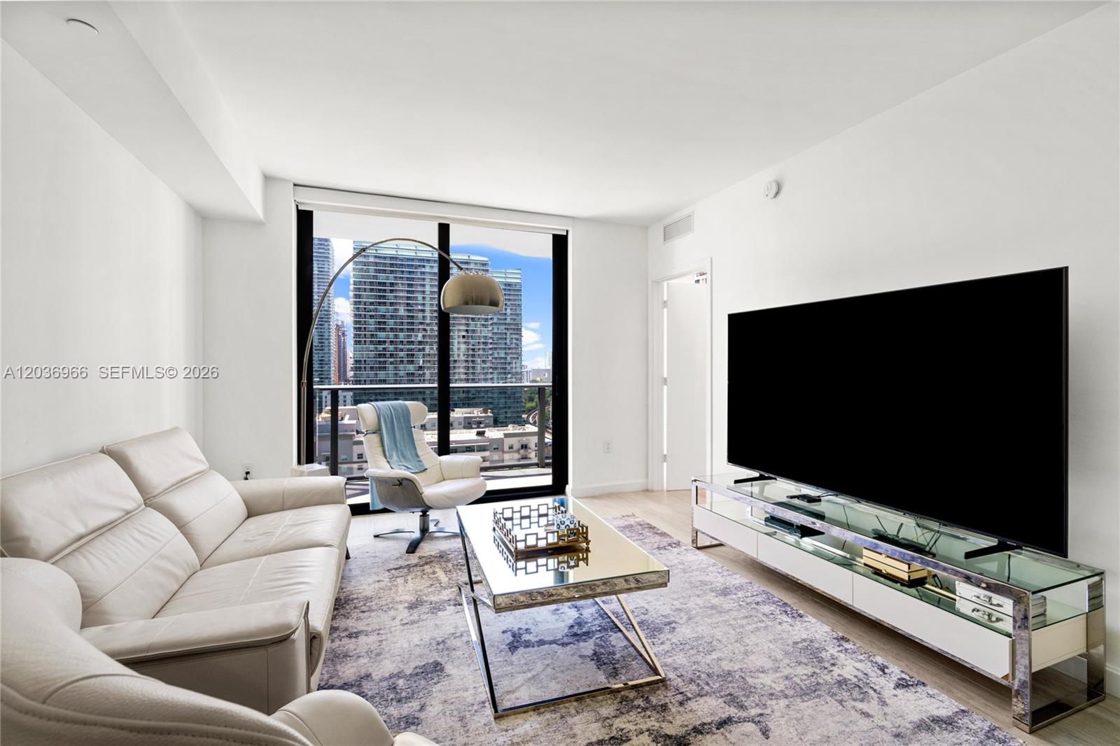 55 Southwest 9th Street, Unit 1904 Miami, FL 33130 - Photo 10 of 66 a living room with furniture a flat screen tv and a floor to ceiling window