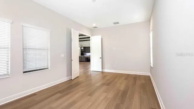 an empty room with wooden floor and windows