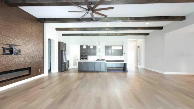 a view of a hallway with kitchen island stainless steel appliances wooden floor and living room view