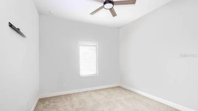 an empty room with a ceiling fan and a window
