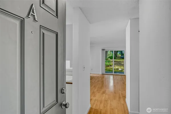 a view of a hallway with wooden floor and a bathroom