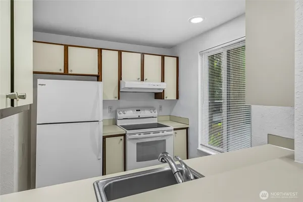 a kitchen with a refrigerator a stove top oven cabinetry and a refrigerator