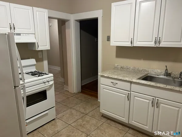 a kitchen with granite countertop white cabinets and white appliances