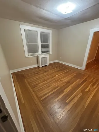 a view of empty room with wooden floor and window